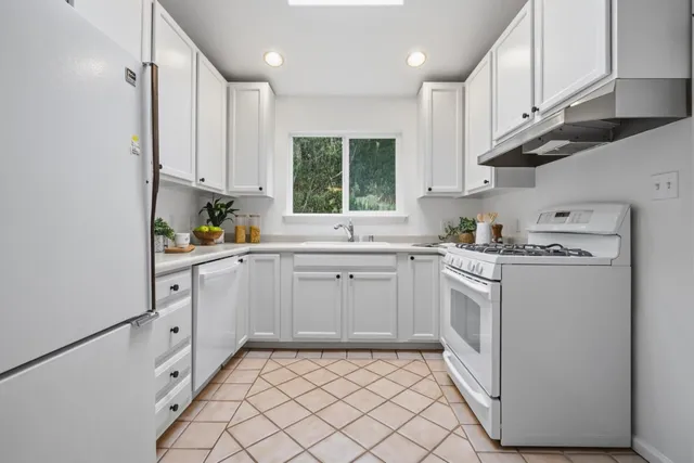 a kitchen with white cabinets and white appliances