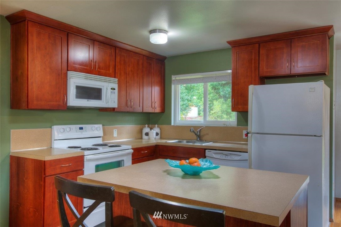 4209 Northeast 11th Street Renton, WA 98059 - Photo 3 of 17 a kitchen with stainless steel appliances wooden cabinets a stove a microwave a sink and a refrigerator