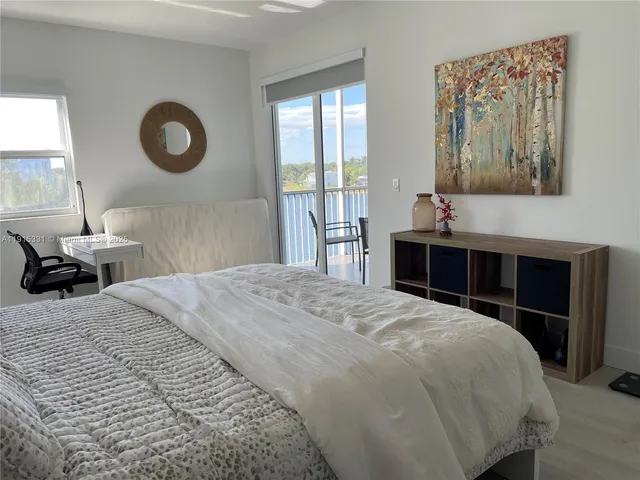 a bedroom with a bed and a lamp on dresser next to a window