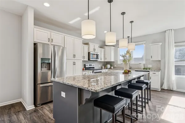 a large kitchen with granite countertop a counter space stainless steel appliances and a chandelier