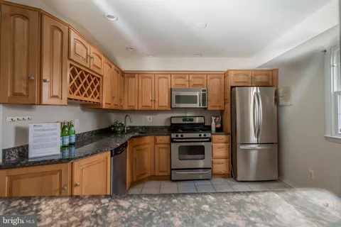 a kitchen with stainless steel appliances granite countertop a refrigerator a stove top oven a sink and dishwasher