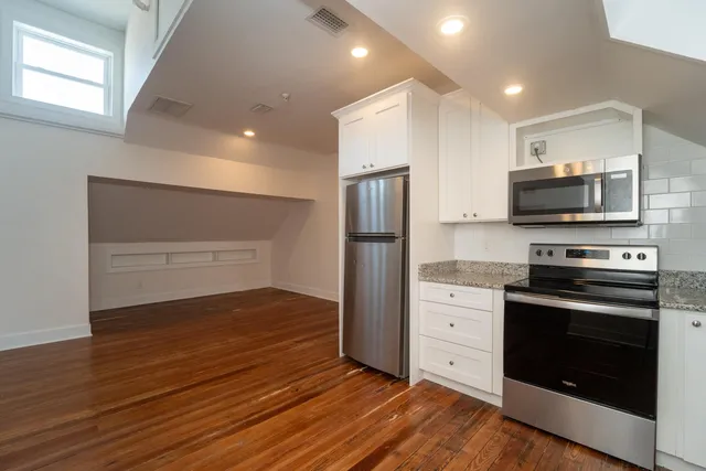a kitchen with a refrigerator stove and wooden floor