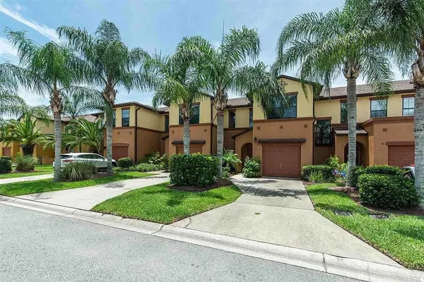 front view of house with a yard and palm trees