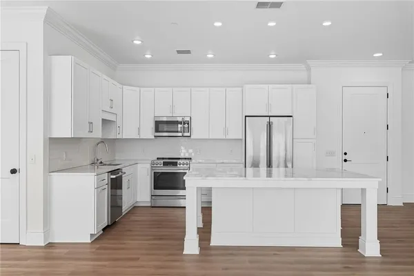 a kitchen with stainless steel appliances kitchen island granite countertop a stove a sink and white cabinets