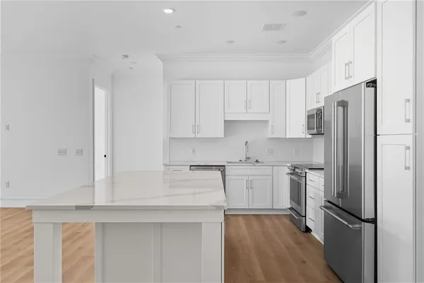 a kitchen with stainless steel appliances granite countertop a refrigerator sink and white cabinets