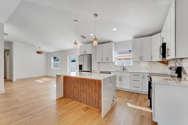 a large kitchen with cabinets wooden floor and stainless steel appliances