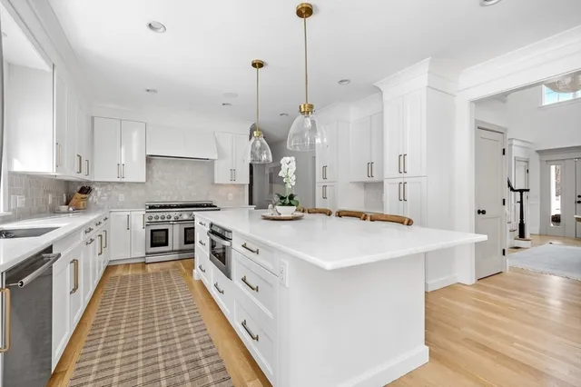 a large kitchen with stainless steel appliances a stove a sink a center island and a wooden floor