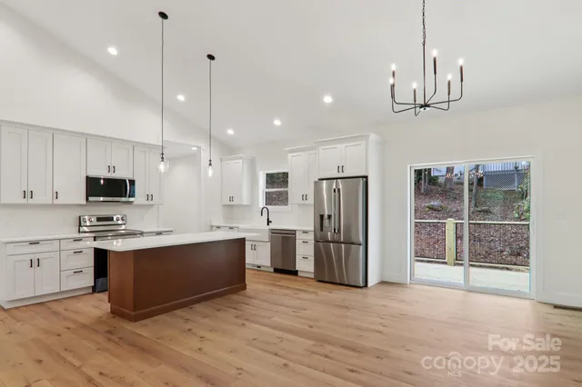 a kitchen with stainless steel appliances a stove top oven a refrigerator a sink and kitchen island