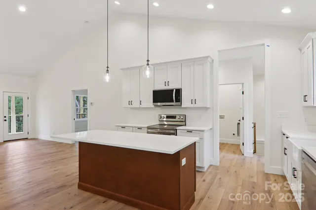 a kitchen with stainless steel appliances a stove top oven a sink a refrigerator a center island and cabinets