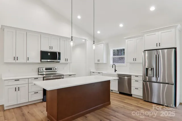 a kitchen with stainless steel appliances a sink stove refrigerator and cabinets