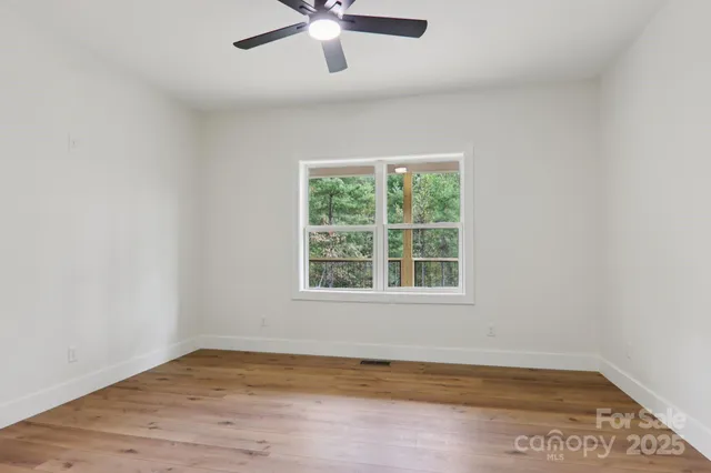 an empty room with wooden floor fan and windows