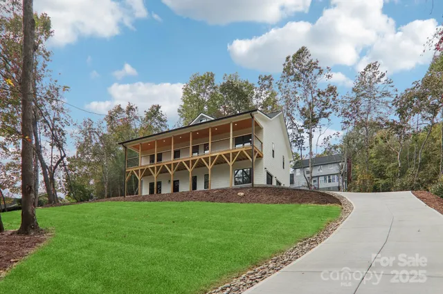 a view of a house with a big yard plants and large trees