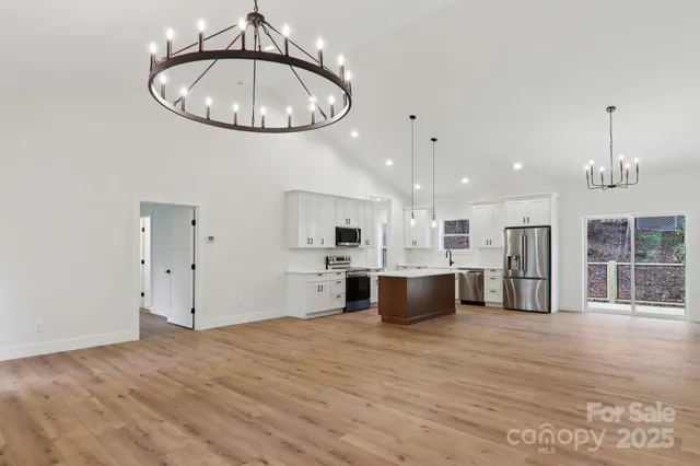 an open kitchen with kitchen island stainless steel appliances granite countertop cabinets and wooden floor