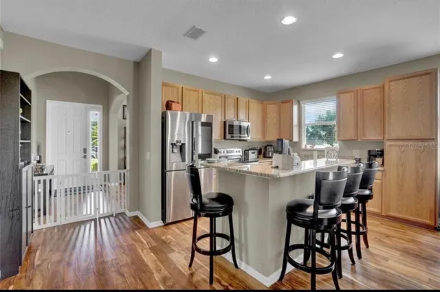 a kitchen with stainless steel appliances a dining table chairs refrigerator and sink