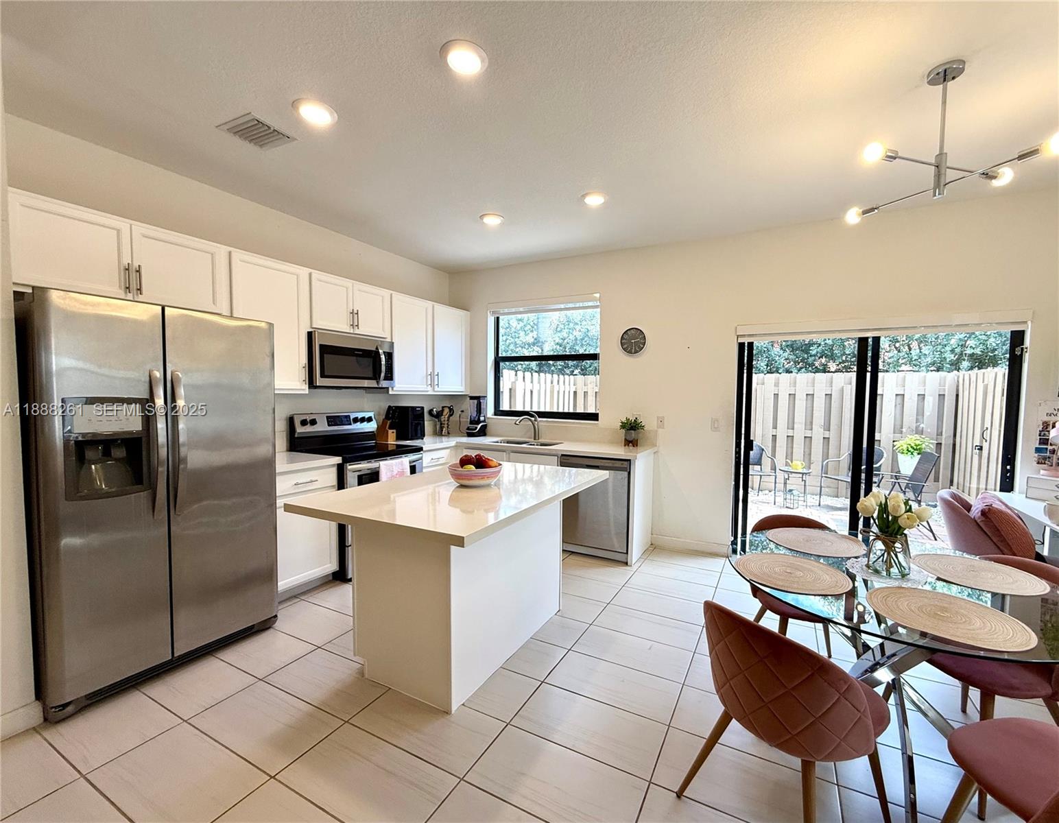 400 Northeast 208th Terrace, Unit 400 Miami, FL 33179 - Photo 4 of 53 a large kitchen with a table chairs refrigerator and cabinets
