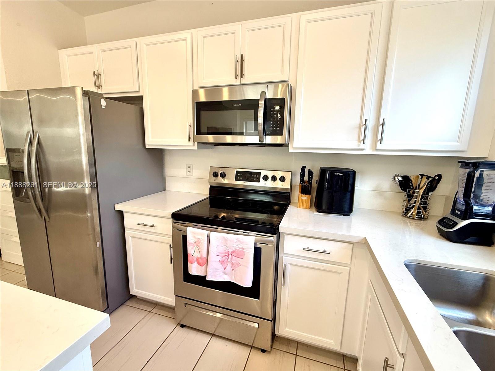 400 Northeast 208th Terrace, Unit 400 Miami, FL 33179 - Photo 6 of 53 a kitchen with stainless steel appliances a stove a microwave and a counter top space