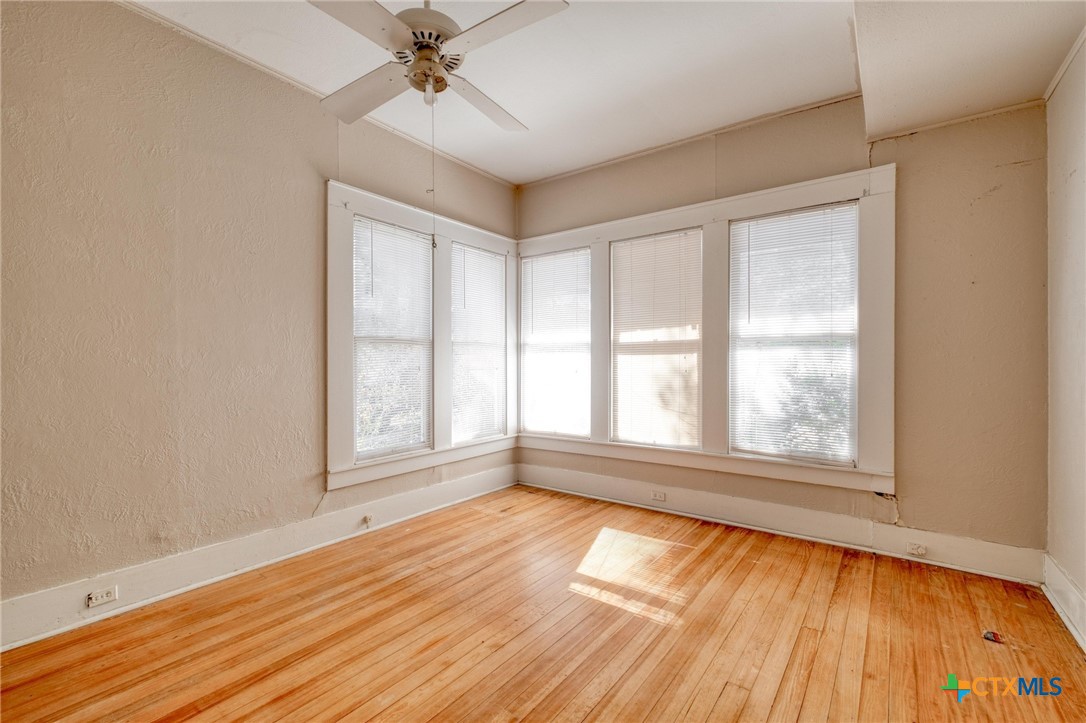 409 East Bowie Street Luling, TX 78648 - Photo 11 of 22 an empty room with wooden floor fan and windows