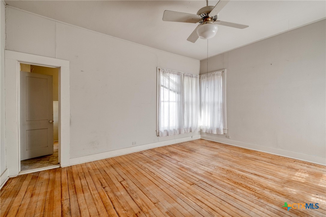 409 East Bowie Street Luling, TX 78648 - Photo 16 of 22 a view of an empty room with wooden floor and a window