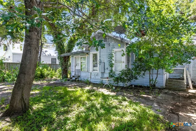 a view of a house with a small yard and a large tree
