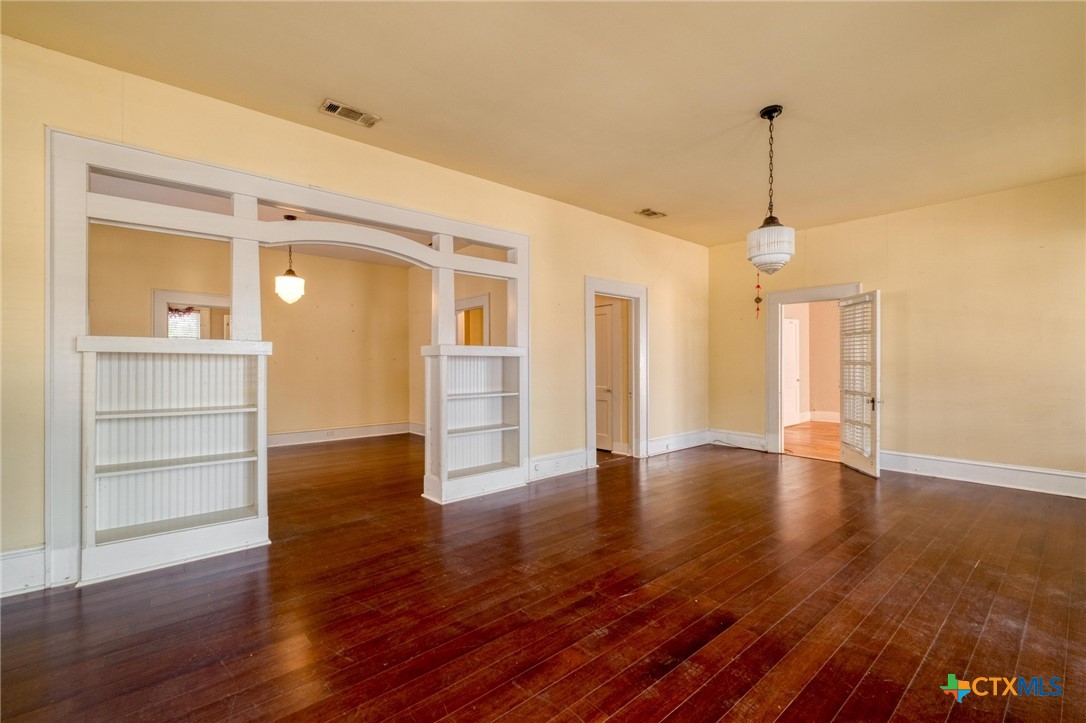 409 East Bowie Street Luling, TX 78648 - Photo 3 of 22 a view of an empty room with wooden floor and a window