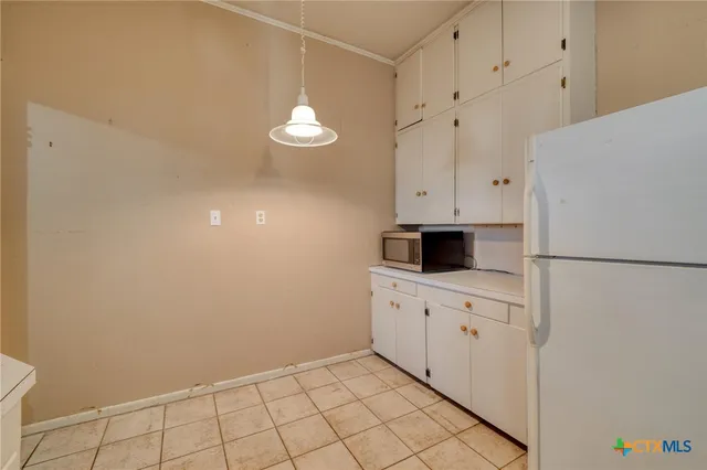a kitchen with white cabinets and refrigerator