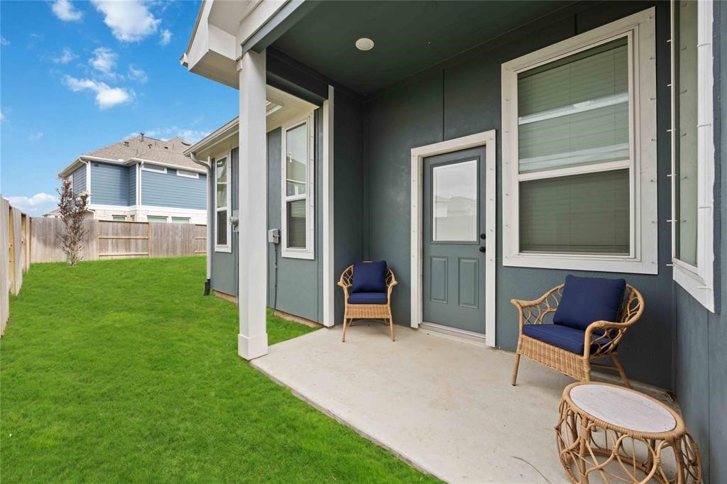 10014 Nectar Path Iowa Colony, TX 77583 - Photo 23 of 26 This photo showcases a cozy backyard patio with two wicker chairs and a small table, adjacent to a well-maintained lawn. The space is inviting and ideal for relaxation or outdoor gatherings.