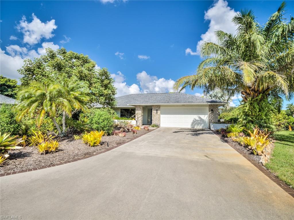 106 Cherry Hill Court Naples, FL 34113 - Photo 2 of 19 a front view of a house with a yard and a garden