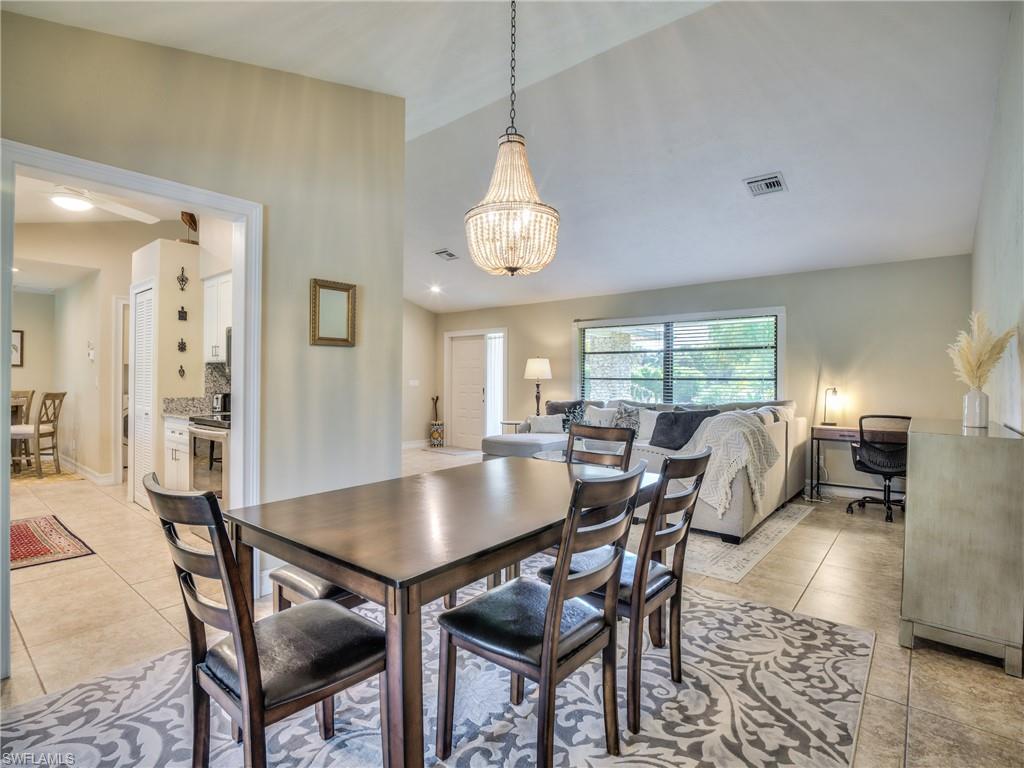 106 Cherry Hill Court Naples, FL 34113 - Photo 6 of 19 a dining room with wooden floor a chandelier a wooden table and chairs