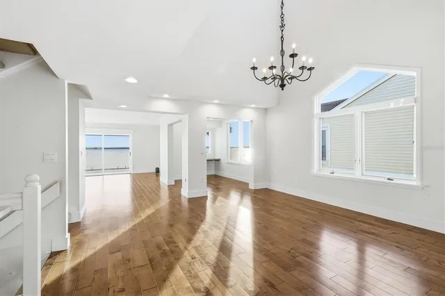 a view of an empty room with kitchen and window