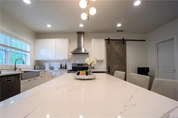 a kitchen with stainless steel appliances kitchen island granite countertop a table chairs sink and microwave