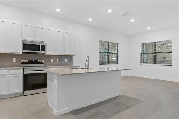 a view of an empty room with kitchen appliances and a large window