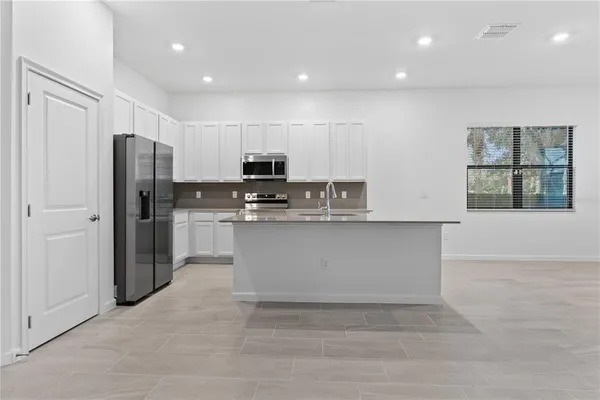 a kitchen with stainless steel appliances granite countertop a refrigerator sink and white cabinets