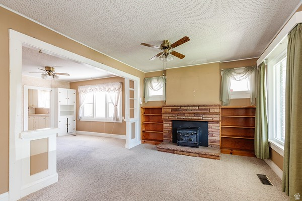 365 West 200 North Logan, UT 84321 - Photo 4 of 45 Living area featuring a brick fireplace with a wood-burning stove insert, built-in shelving, and carpet flooring