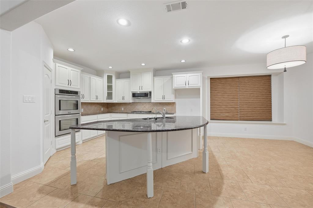 1321 Talley Lane Frisco, TX 75033 - Photo 11 of 40 Kitchen with glass insert cabinets, dark stone countertops, white cabinetry, tasteful backsplash, and a breakfast bar area