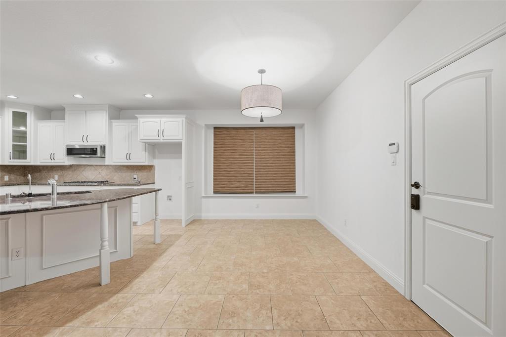 1321 Talley Lane Frisco, TX 75033 - Photo 12 of 40 Kitchen featuring tasteful backsplash, white cabinetry, dark stone counters, a breakfast bar, and glass insert cabinets