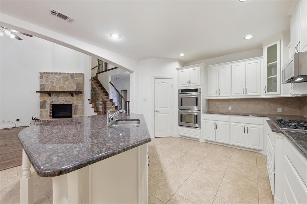 1321 Talley Lane Frisco, TX 75033 - Photo 38 of 40 Kitchen featuring decorative backsplash, a fireplace, open floor plan, dark stone counters, and recessed lighting