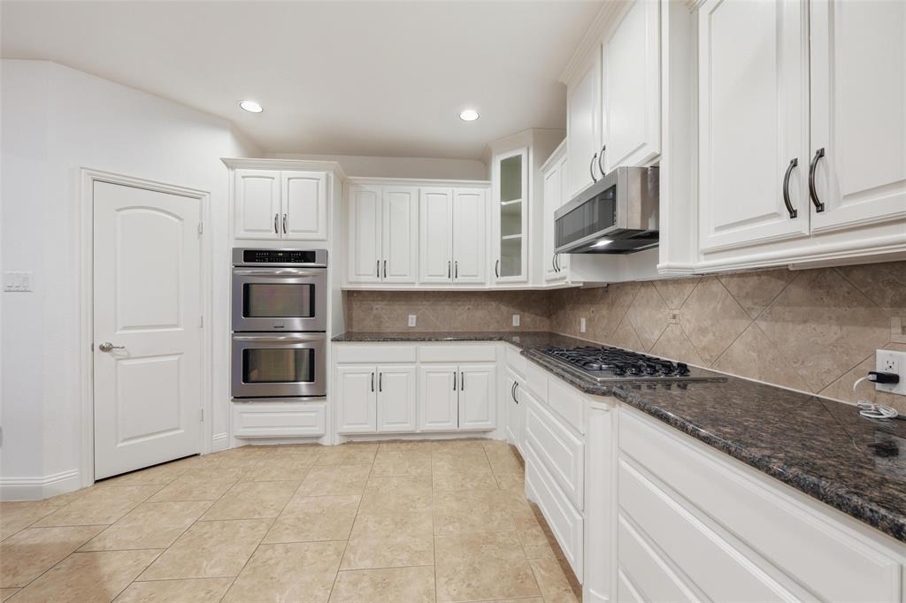 1321 Talley Lane Frisco, TX 75033 - Photo 13 of 40 Kitchen with backsplash, appliances with stainless steel finishes, white cabinetry, light tile patterned floors, and glass insert cabinets