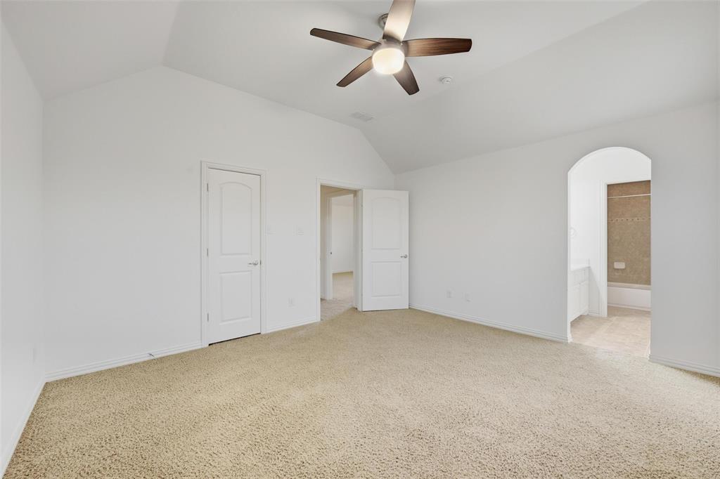 1321 Talley Lane Frisco, TX 75033 - Photo 20 of 40 Unfurnished bedroom featuring vaulted ceiling, arched walkways, light carpet, ceiling fan, and ensuite bath