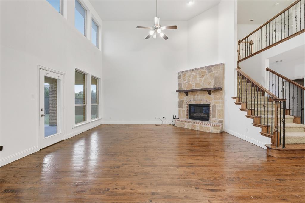 1321 Talley Lane Frisco, TX 75033 - Photo 8 of 40 Unfurnished living room featuring a fireplace, dark wood finished floors, ceiling fan, a high ceiling, and stairway