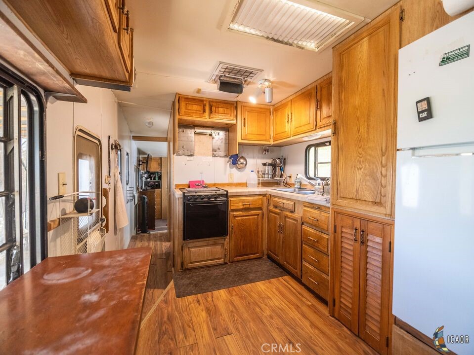 4898 Forrester Road Brawley, CA 92227 - Photo 9 of 10 a kitchen with stainless steel appliances granite countertop a refrigerator a sink dishwasher and a stove with wooden floor