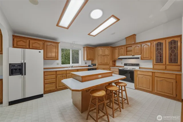 a kitchen with stainless steel appliances granite countertop a stove a refrigerator a sink a dining table and chairs with wooden floor