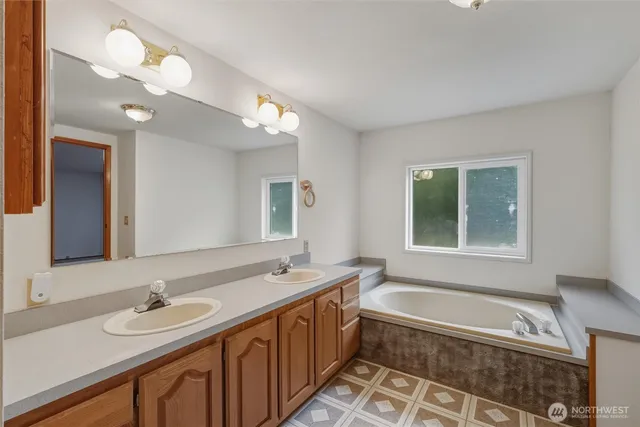 a bathroom with a tub a sink and a large mirror