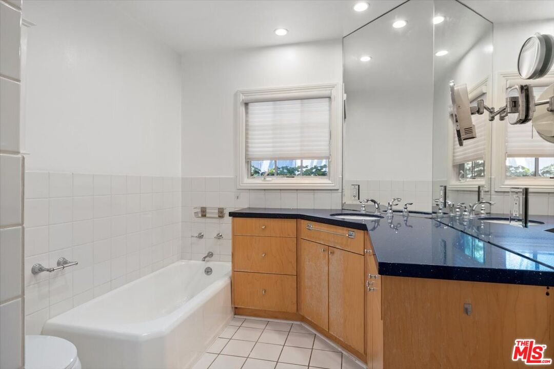 14041 Roblar Road Sherman Oaks, CA 91423 - Photo 25 of 47 a bathroom with a granite countertop sink mirror vanity bathtub and next to a window