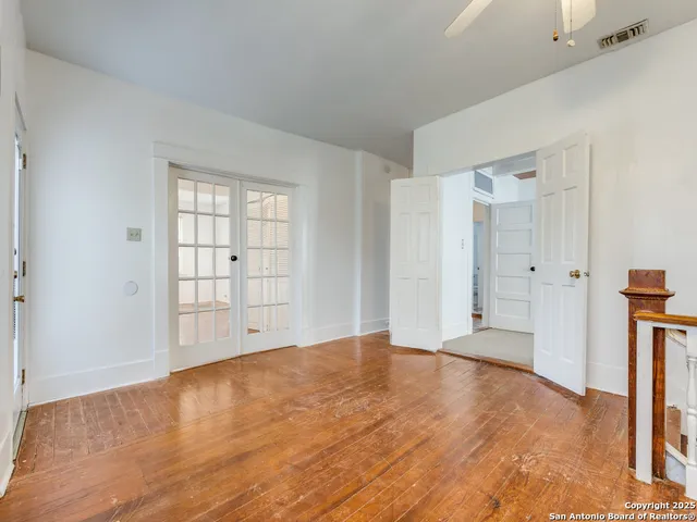 a view of an empty room with window and wooden floor