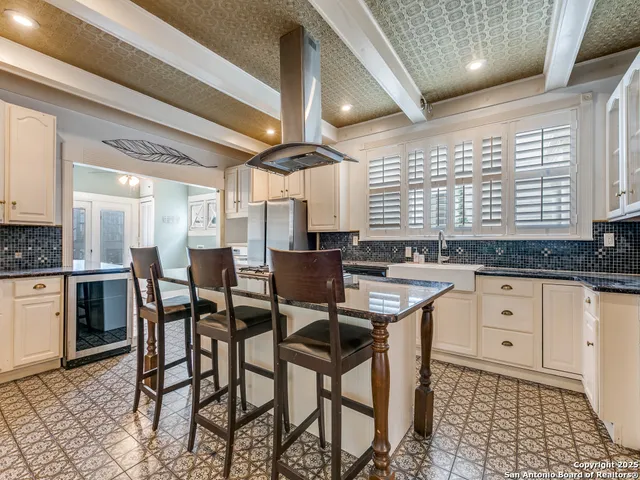 a kitchen with stainless steel appliances kitchen island granite countertop a table chairs sink and cabinets