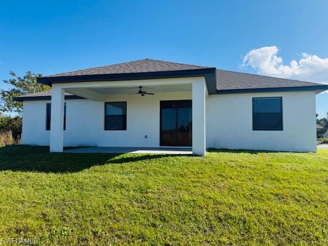 165 Patio Street Lehigh Acres, FL 33974 - Photo 9 of 34 Back of house featuring ceiling fan, a patio, a yard, stucco siding, and roof with shingles