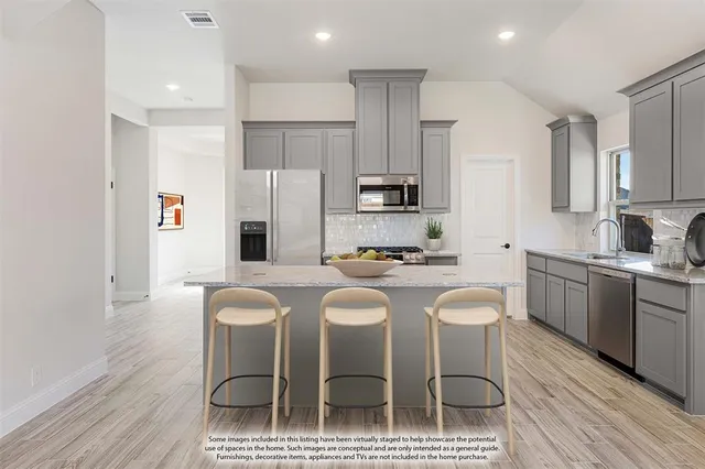 a kitchen with stainless steel appliances a dining table chairs refrigerator and sink
