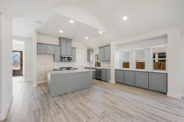 a large kitchen with a lot of counter space and wooden floor