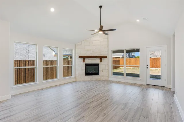 a view of an empty room with wooden floor fireplace and a window