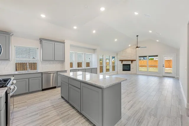 a large kitchen with stainless steel appliances kitchen island granite countertop a large counter top and a stove